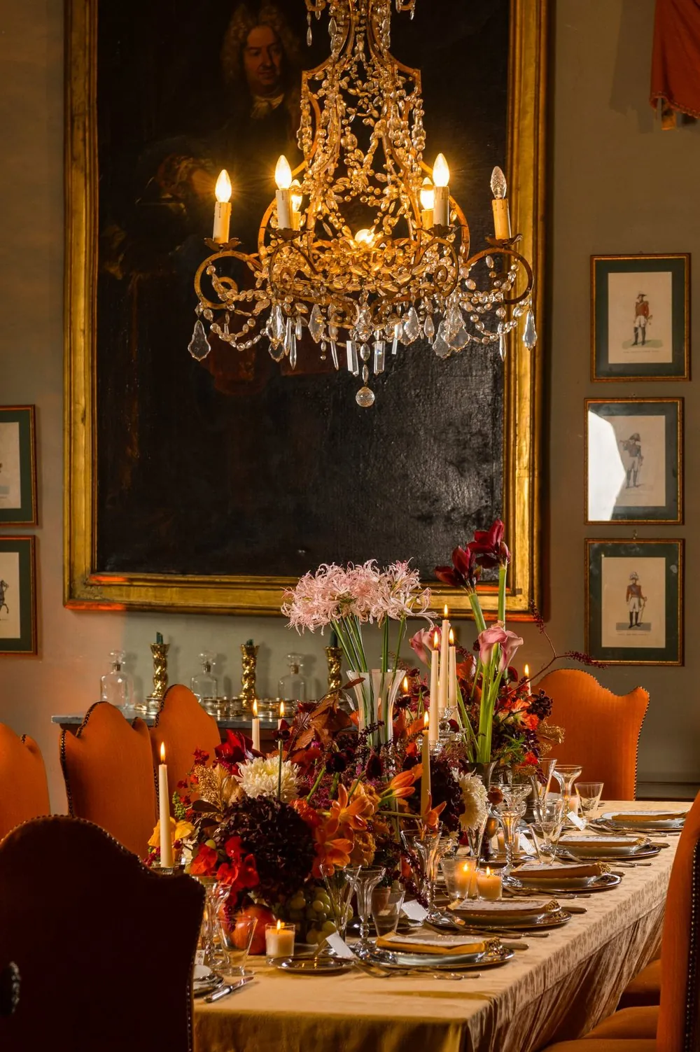 La camera da pranzo apparecchiata a lume di candela, con il lampadario di cristallo e il grande ritratto in cornice dorata