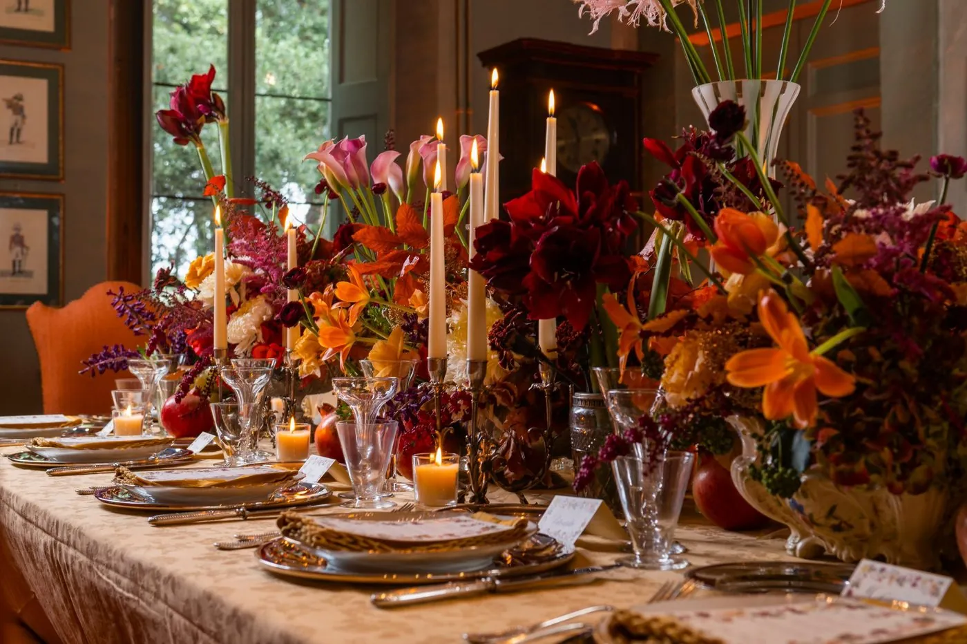 The table laid in the dining room, with lit candles and arrangements of red and orange flowers