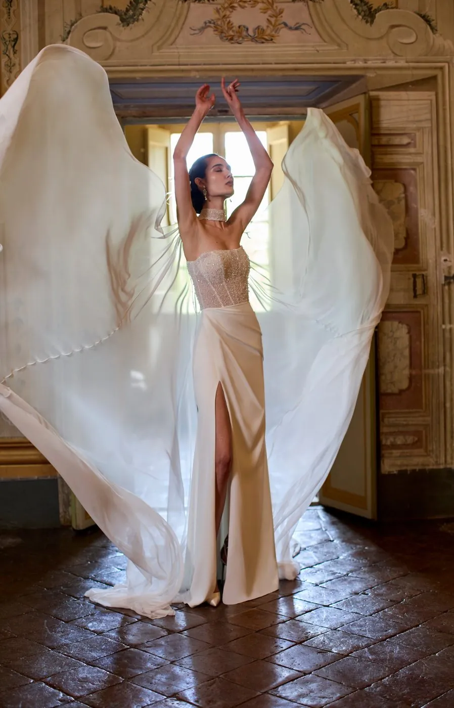 A wedding dress with a long flowing veil, in a frescoed room