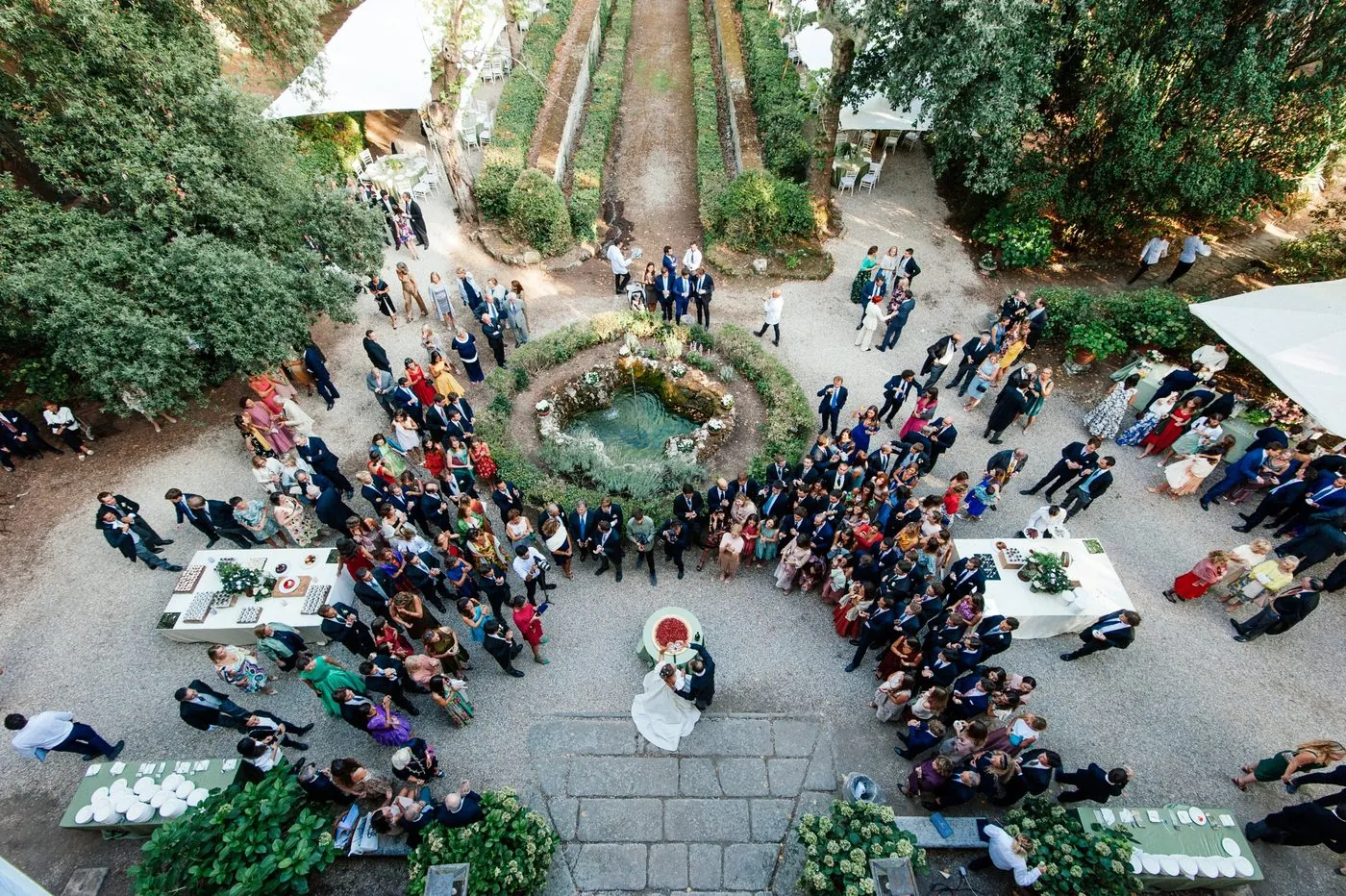 The couple cutting the cake at the foot of the steps, surrounded by guests in the garden, seen from above