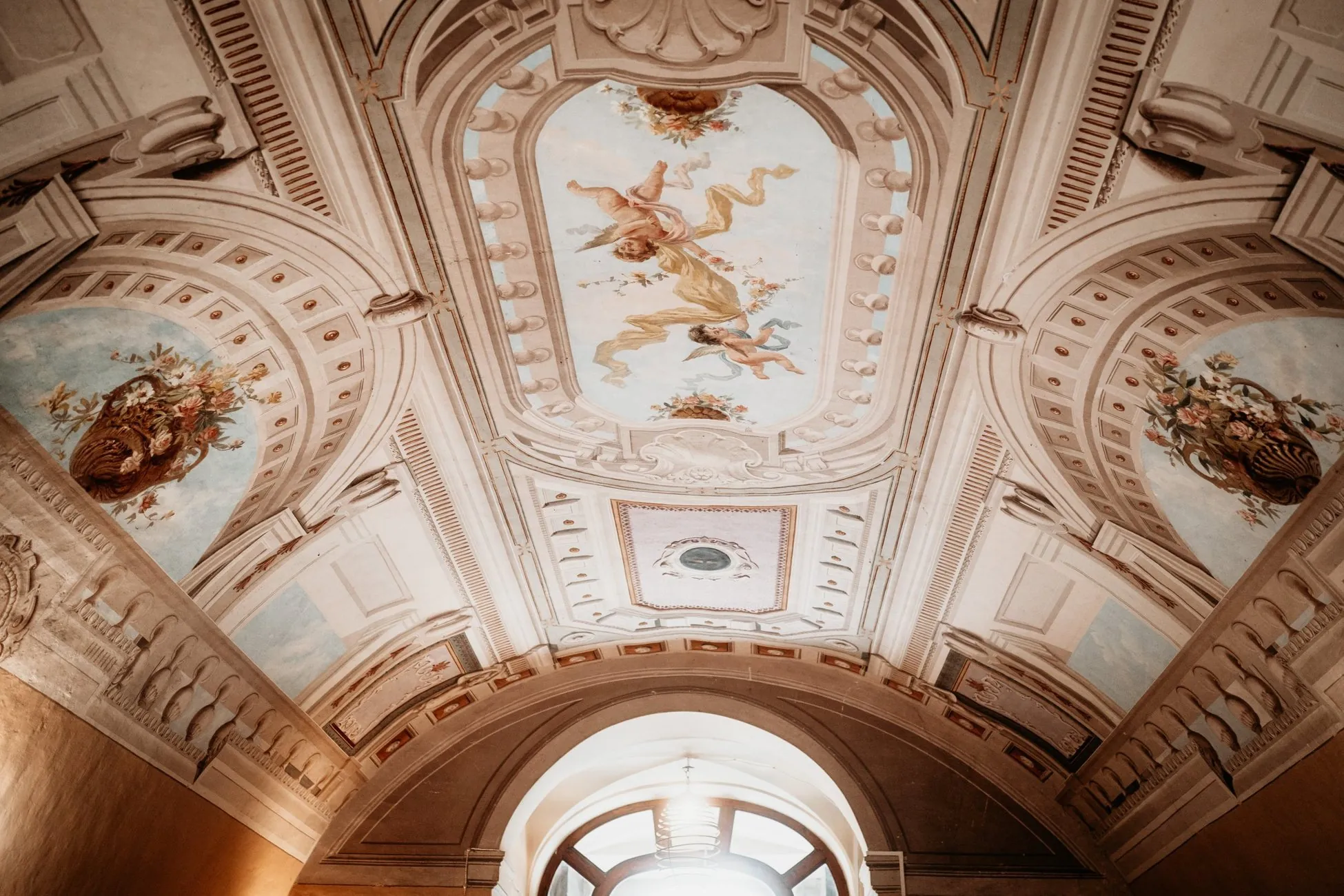 Il soffitto affrescato con putti e cesti di fiori sopra un passaggio ad arco