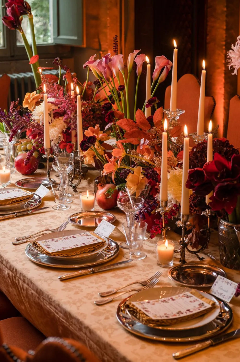 Tavola apparecchiata per una cena privata, con fiori d'autunno, candele, argenti e cristalli