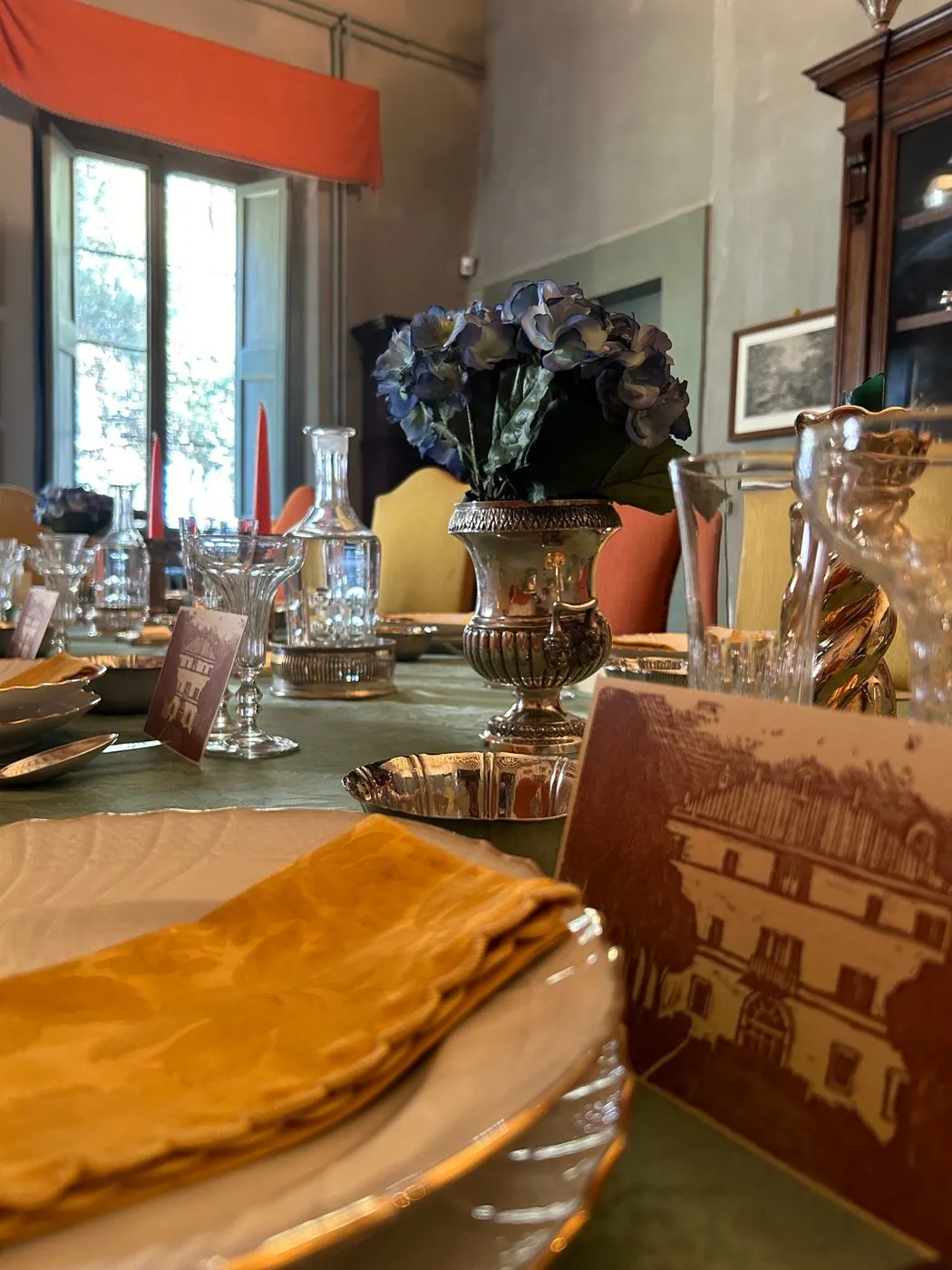 A table laid with silver, crystal and place cards bearing a drawing of the villa